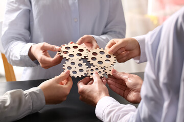 Group of business people holding wooden gears at table