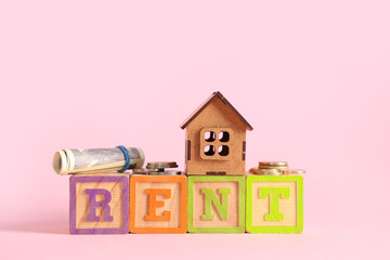 Toy house with word RENT and money on pink background