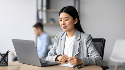 Asian Professional Woman Engaged in Virtual Communication for Team Meeting in Office