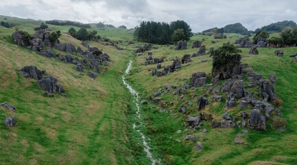 Fototapeta premium Rolling green hills with limestone rock formations dotting the landscape in Waitomo, Waitanguru, Te Kuiti, Waikato, New Zealand. The unique landscape is a popular tourist destination.