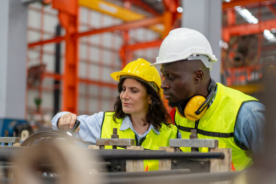female engineer supervisor advice technician foreman to inspect and check spare part equipment of production machine, team of diverse workers working together at industrial manufacturing factory