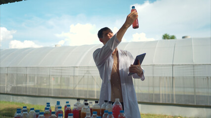 A researcher in a lab coat uses a tablet to inspect colorful liquid samples
