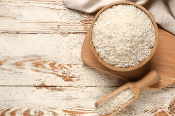 Bowl and scoop with raw rice on white wooden background