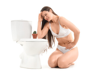Suffering young woman near toilet bowl on white background. Cystitis concept