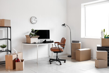 Interior of office with workplace, lamp and cardboard boxes on moving day