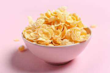 Bowl with tasty cornflakes on pink background, closeup