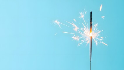 Fototapeta premium A sparkling sparkler emitting bright light against a light blue background