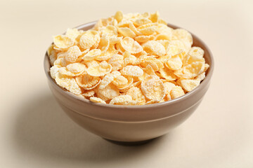 Bowl with tasty cornflakes on beige background, closeup