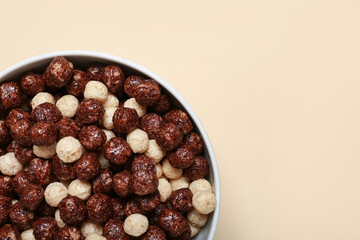 Bowl with tasty chocolate corn balls on beige background, closeup