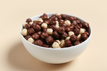 Bowl with tasty chocolate corn balls on beige background, closeup