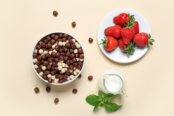 Plate with strawberry and bowl with chocolate corn balls on beige background