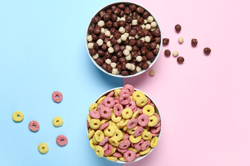 Bowls with chocolate corn balls and color cereal rings on color background, closeup
