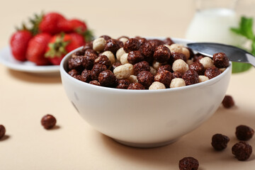 Bowl with chocolate corn balls on beige background, closeup