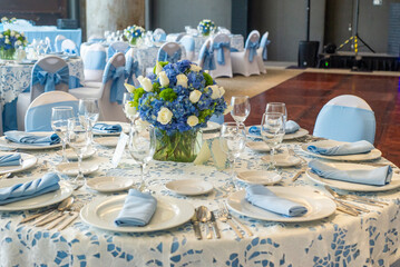 A blue and white table setting with a vase of flowers and a bowl of fruit