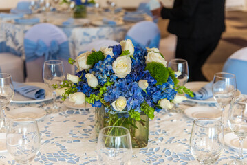 A table with a blue and white tablecloth and a vase of flowers in the center