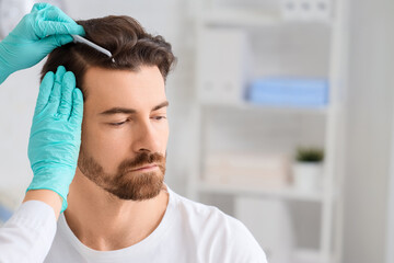 Naklejka premium Doctor examining man in clinic. Hair loss problem