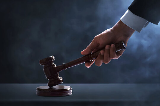 Judge hand striking gavel on dark smoke background