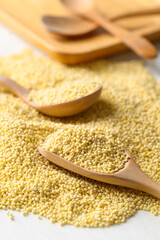 Yellow millet grain in wooden spoon, Food ingredient