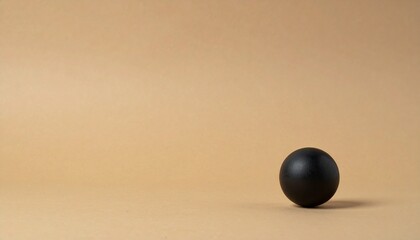 上からの優しい光に包まれたマットな黒い球が砂色の落ち着いた背景に映える様子

