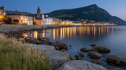 Coastal town at twilight with illuminated buildings reflected in the water.