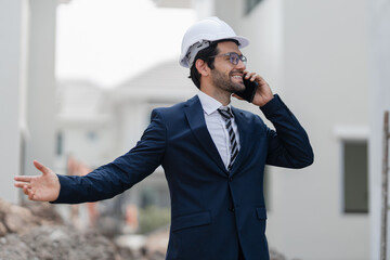 engineer handsome man or architect looking forward with white safety helmet in construction site. Standing at modern building construction. Worker man working project building home village.