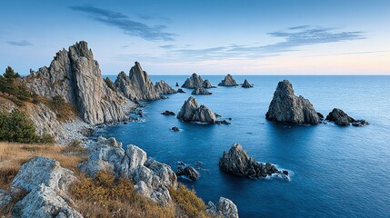 Rocky coastline meets a tranquil ocean at dawn.