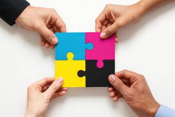 Four diverse hands holding a CMYK puzzle