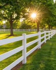 A beautiful sunrise illuminating a white fence and lush greenery in a serene landscape.