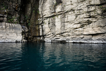 Emerald river water of Dawki flows between sheer rock cliffs, serene natural beauty.