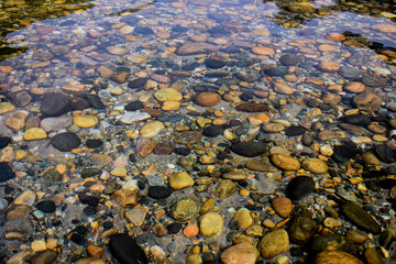 Smooth, colorful Dawki river rocks visible through clear water.
