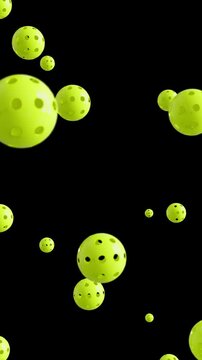 Pickle balls falling down with seamless loop on black background, vertical video