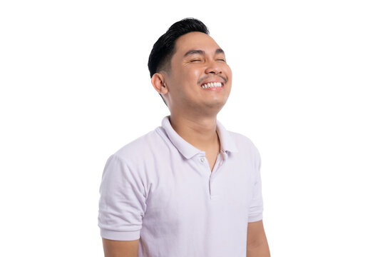 Happy young Asian man in white polo shirt smiling with eyes closed looking up isolated on transparent background
