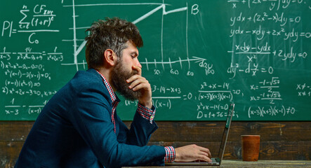 Teacher explains math at blackboard. Professor in classroom with chalkboard. University professor writes math formula. Bearded teacher. Professor teaching lesson in classroom. Professor explains math.