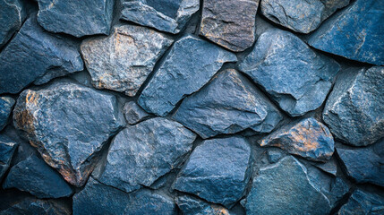 A close-up image of an interlocking stone wall composed of irregular, natural stone slabs in various shades of blue and slate gray. The surface shows natural cracks and subtle earthy undertones.