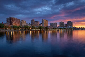 Naklejka premium City skyline reflected in water under a dramatic sky at dusk with building lights