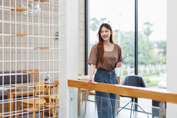 Attractive asian woman, Manager with laptop stands in office area of coworking space
