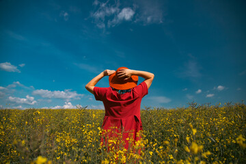 Trendy woman with stylish hat feeling free in the field with flowers