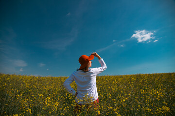 Trendy woman with stylish hat feeling free in the field with flowers