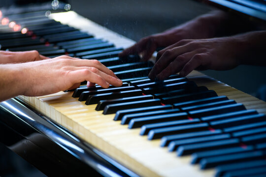 A piano keyboard being played, showing hands only.