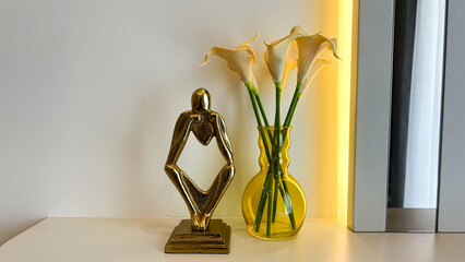 Modern Interior Still Life With Golden Abstract Sculpture And Yellow Vase With Calla Lilies On A White Table, Daylight, Minimalist Decor Concept, Ideal For Branding, Lifestyle, And Interior Design