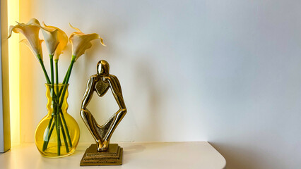Yellow Vase With Calla Lilies And Golden Abstract Sculpture On A White Table, Minimalist Interior Scene With Copy Space, Soft Lighting, Ideal For Mindfulness, Branding, And Interior Concepts