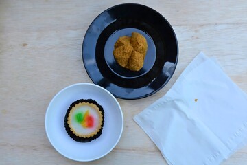 A close-up shot of a single, beautifully risen huat kueh (steamed cake) and mini tart with a...