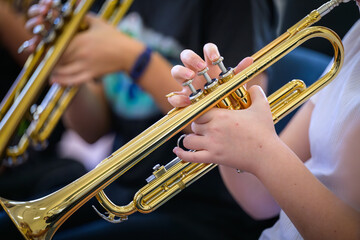 A trumpet being played by a youth in the foreground with other trumpets blurred in the background.