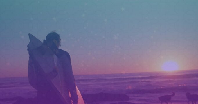 Travel showing man entering shoreline carrying surfboard pausing admiring sinking sun dogs trotting