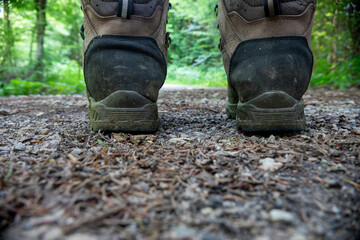 Man stands on forest road woodland shoes. Closeup shot. A pair of brown black boots on a sandy floor. Rear view.