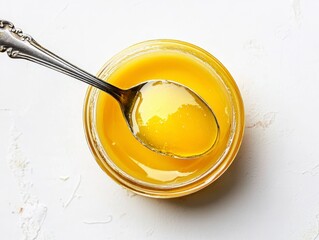Golden Ghee in a Jar with Spoon on White Background