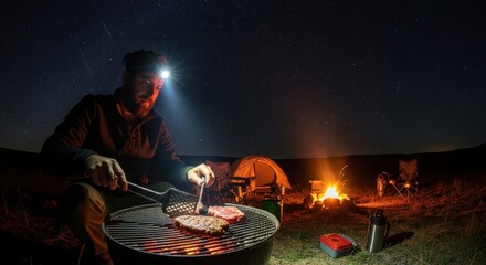 Young caucasian male grilling steak while camping under starry night sky