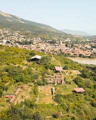 Panoramic aerial view of Armaziskhevi ruins with Mtskheta town, Svetitskhoveli Cathedral, and surrounding Caucasus hills in summer