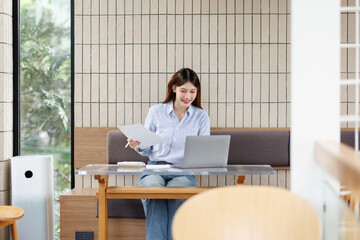  Portrait of young business woman using a calculator to check company finances and earnings and...