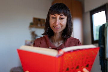Happy girl sitting on the sofa and reading a book, smiling at home, Relaxation, free time, home...